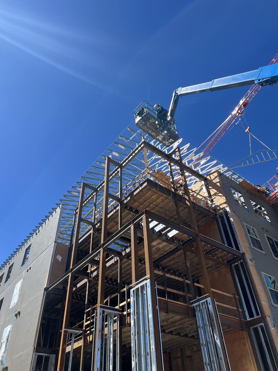 Steel trusses being set by crane on a mid rise multifamily structure